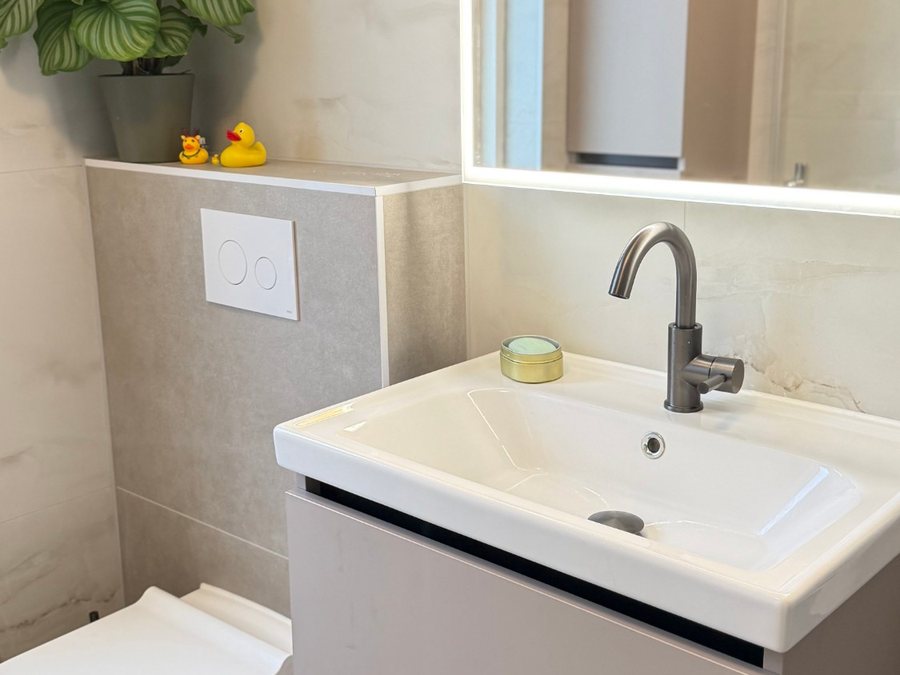 Badmeubel in taupe met wastafel en LED-spiegel naast een hangtoilet met ingebouwd reservoir
